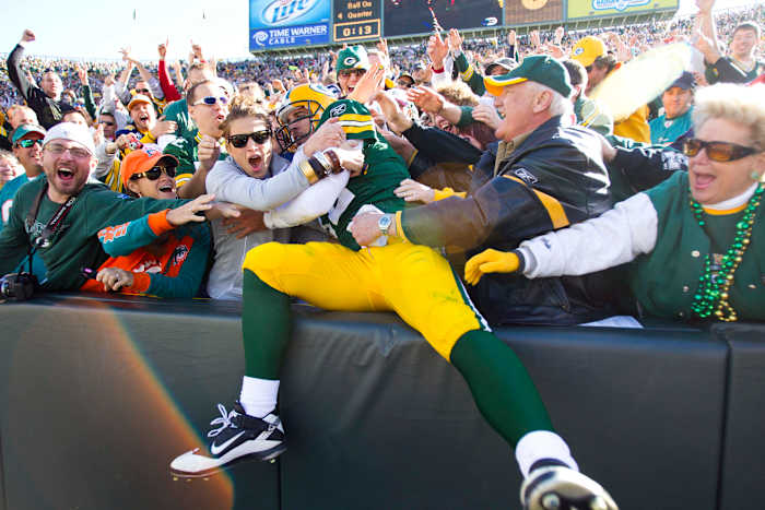 Green Bay Packers quarterback Aaron Rodgers leaps into the stands to celebrate a touchdown.